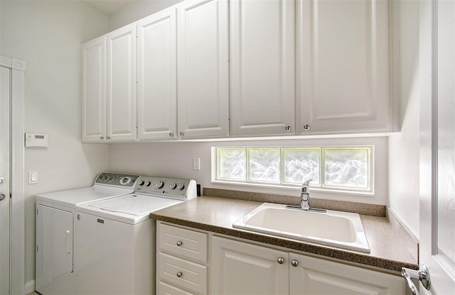 laundry room with washing machine and clothes dryer, sink, and cabinets