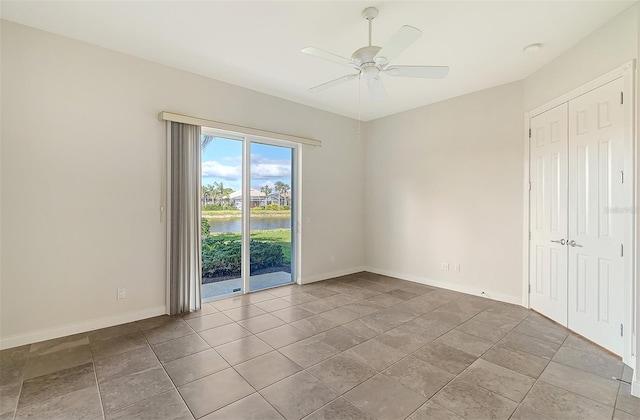 unfurnished room with ceiling fan and a water view