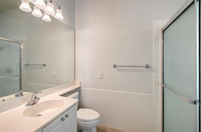 bathroom featuring an enclosed shower, vanity, toilet, and tile walls