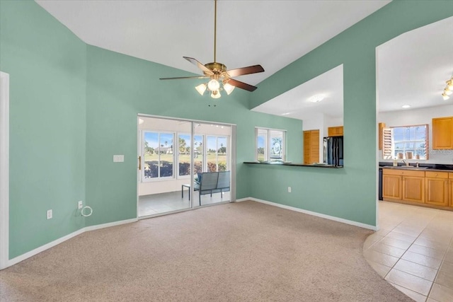 unfurnished living room featuring ceiling fan, sink, and light carpet