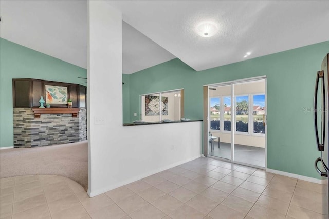 tiled empty room with a textured ceiling and lofted ceiling