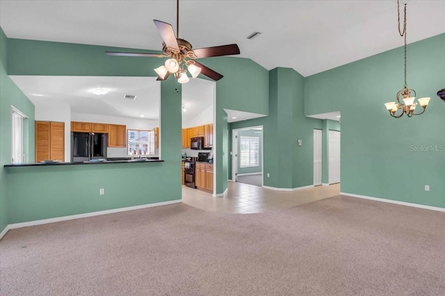 unfurnished living room with ceiling fan with notable chandelier, light colored carpet, and high vaulted ceiling