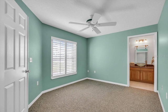 unfurnished bedroom featuring light carpet, a textured ceiling, ensuite bathroom, and ceiling fan