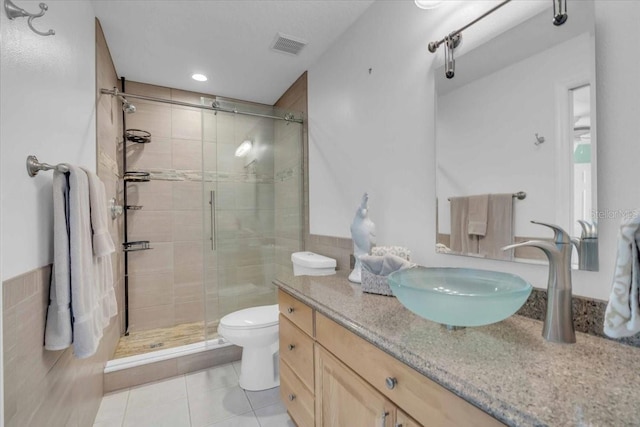 bathroom featuring tile patterned floors, a shower with door, vanity, and toilet