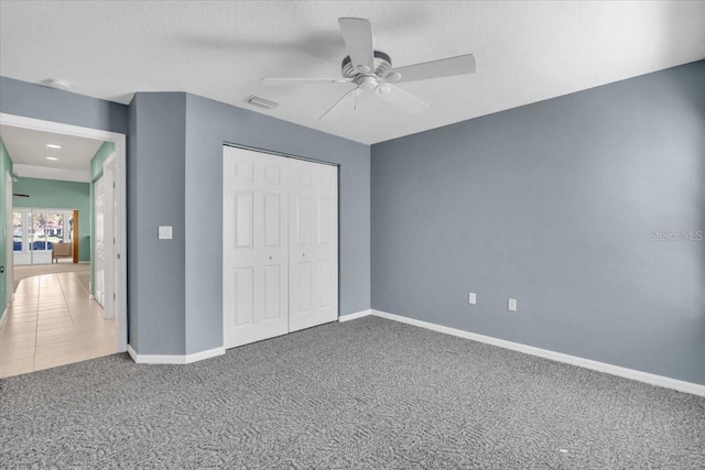 unfurnished bedroom featuring carpet, ceiling fan, and a closet