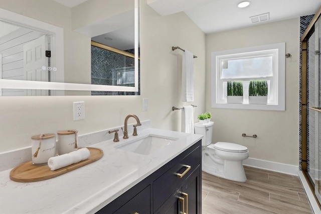 bathroom with a shower with door, vanity, and toilet