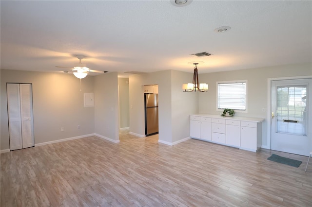 interior space featuring ceiling fan with notable chandelier and light hardwood / wood-style floors