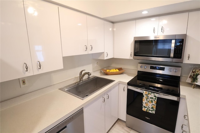 kitchen featuring sink, stainless steel appliances, white cabinetry, and light tile patterned floors