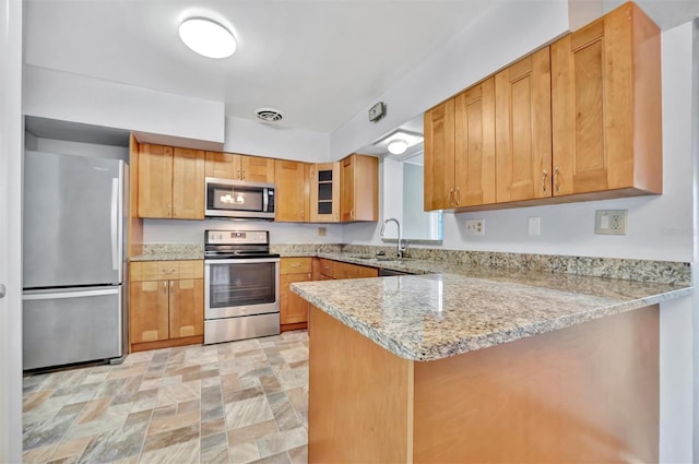 kitchen featuring kitchen peninsula, light stone countertops, sink, and appliances with stainless steel finishes