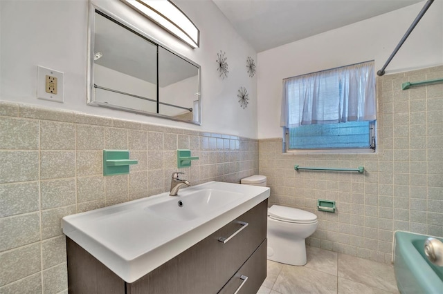 bathroom with toilet, vanity, tile patterned floors, and tile walls