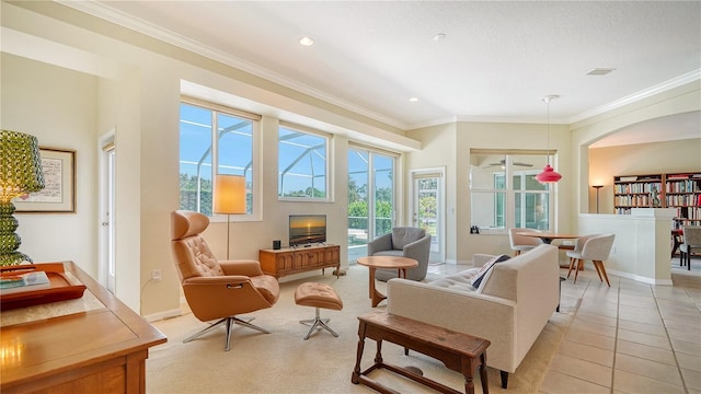 living area with crown molding, a fireplace, and light tile patterned floors