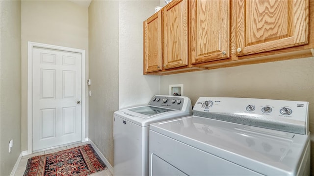 washroom featuring tile patterned floors, washing machine and dryer, and cabinets