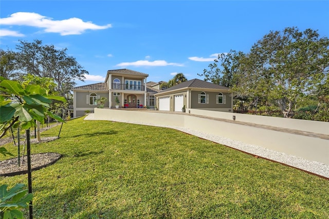 back of property featuring a balcony, a garage, and a lawn