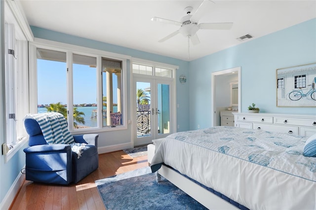 bedroom featuring a water view, dark wood-type flooring, ceiling fan, french doors, and access to exterior