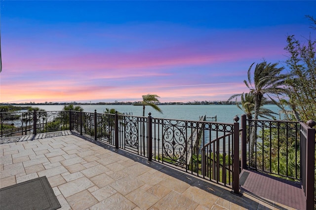 patio terrace at dusk with a water view and a balcony