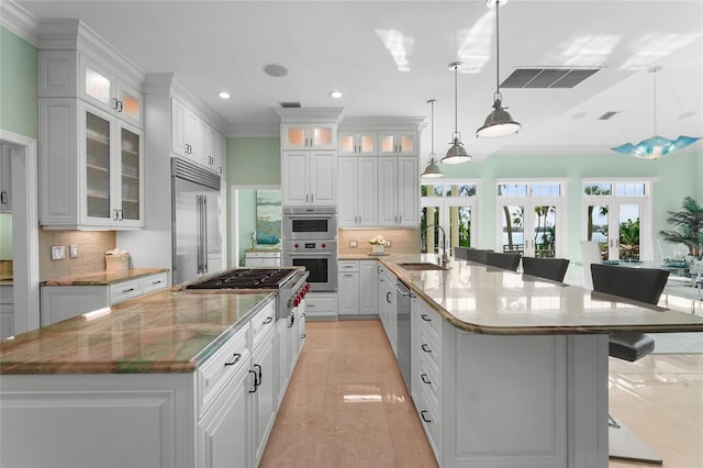 kitchen featuring a kitchen bar, appliances with stainless steel finishes, decorative light fixtures, kitchen peninsula, and white cabinets