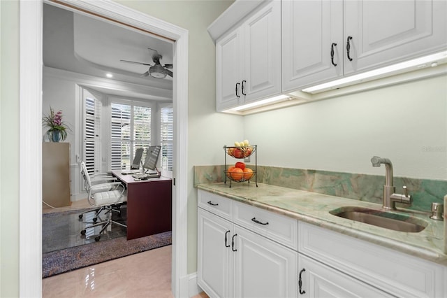 interior space featuring sink, light stone counters, white cabinetry, and ceiling fan