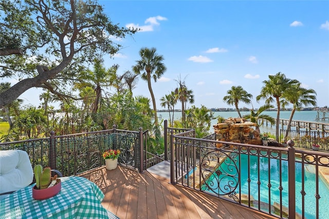 wooden terrace with a water view, a fenced in pool, and grilling area