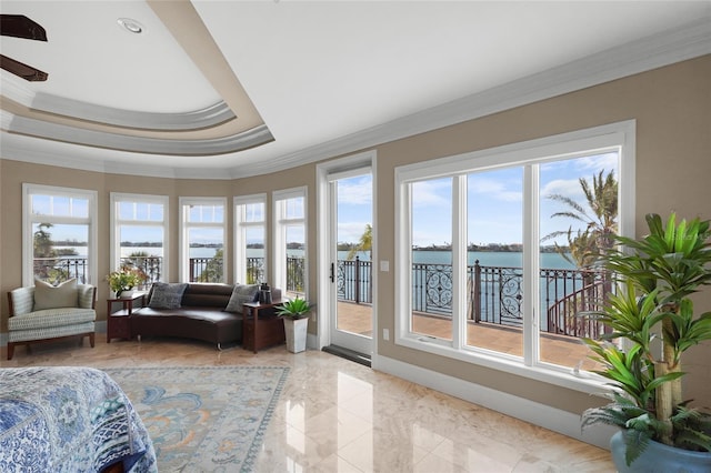 sunroom with a water view, a raised ceiling, and a healthy amount of sunlight