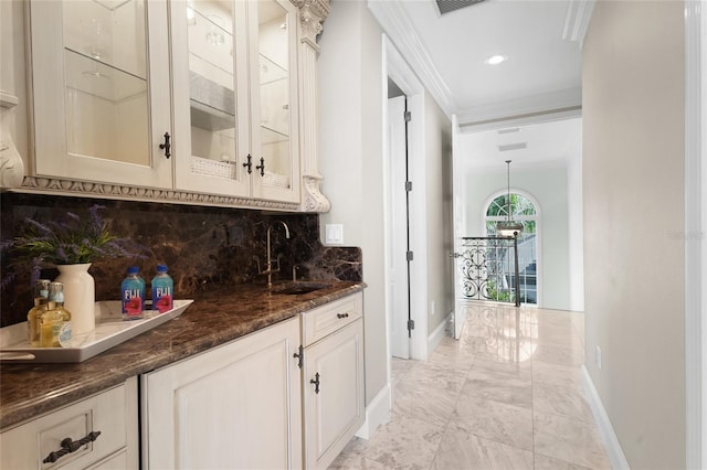 bar featuring white cabinetry, sink, ornamental molding, dark stone counters, and decorative backsplash