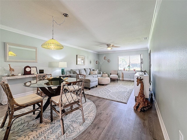 dining space with a textured ceiling, crown molding, ceiling fan, and dark wood-type flooring