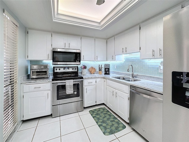 kitchen featuring white cabinetry, sink, a raised ceiling, light tile patterned flooring, and appliances with stainless steel finishes