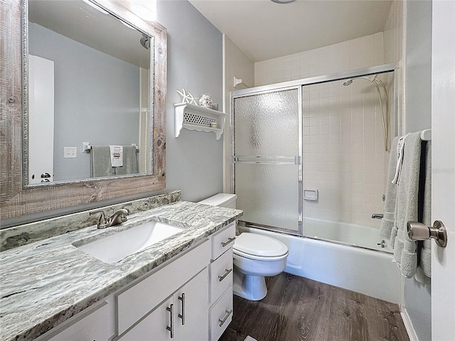 full bathroom with hardwood / wood-style floors, vanity, toilet, and shower / bath combination with glass door