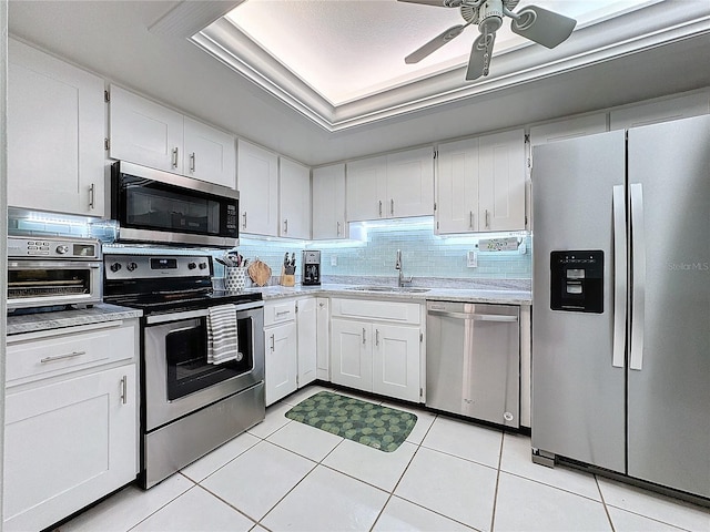 kitchen with white cabinets, appliances with stainless steel finishes, light tile patterned flooring, and sink