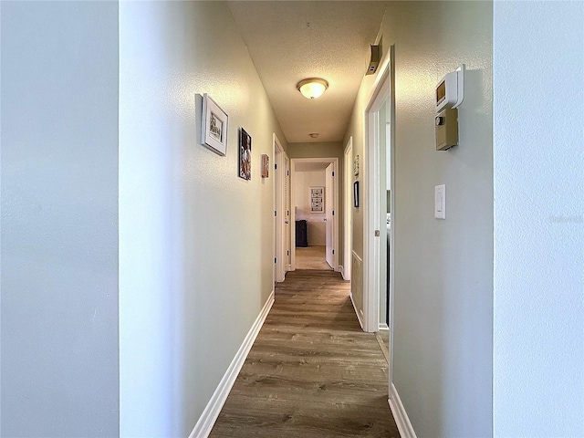 corridor with dark wood-type flooring and a textured ceiling