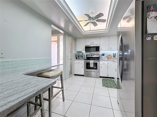 kitchen with white cabinets, decorative backsplash, a raised ceiling, and appliances with stainless steel finishes