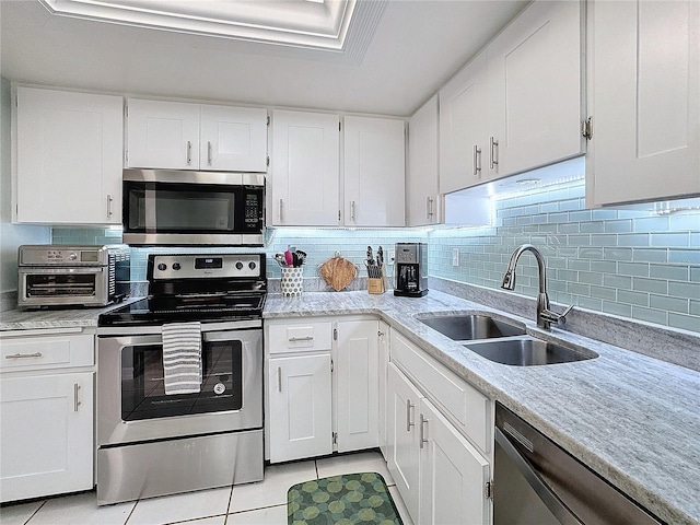 kitchen with light tile patterned flooring, appliances with stainless steel finishes, white cabinetry, and sink