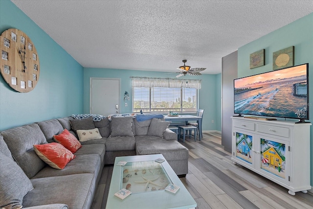 living room featuring ceiling fan, a textured ceiling, and light hardwood / wood-style flooring