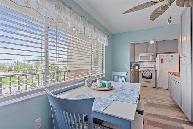 dining area featuring light wood-type flooring, a textured ceiling, and ceiling fan