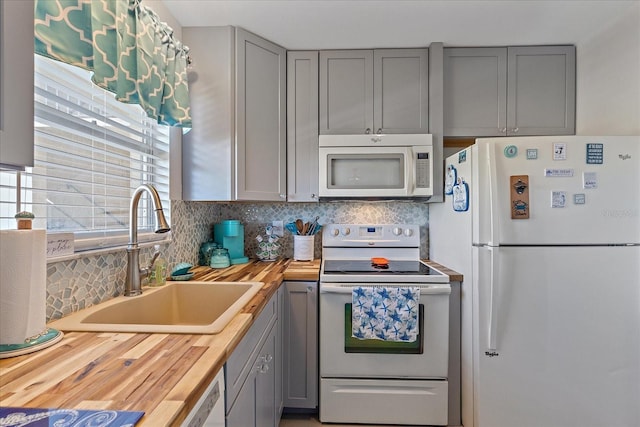 kitchen with butcher block countertops, gray cabinetry, sink, and white appliances