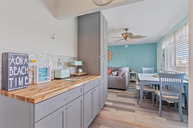 kitchen featuring ceiling fan, wooden counters, light hardwood / wood-style floors, a textured ceiling, and gray cabinets