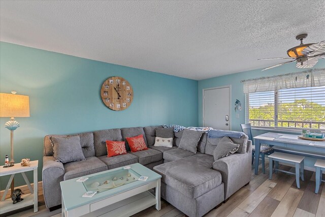 living room with a textured ceiling, light hardwood / wood-style flooring, and ceiling fan