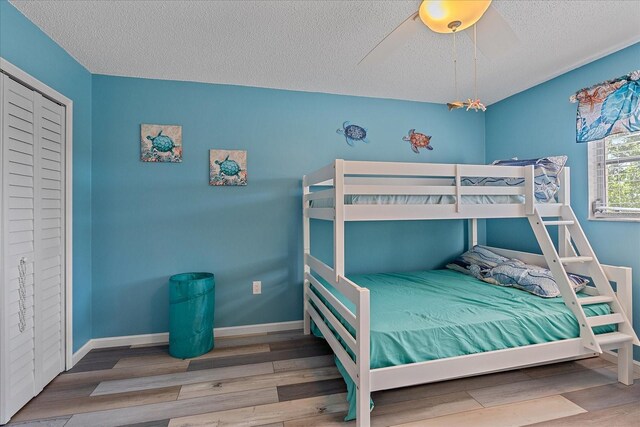 bedroom with ceiling fan, wood-type flooring, and a textured ceiling