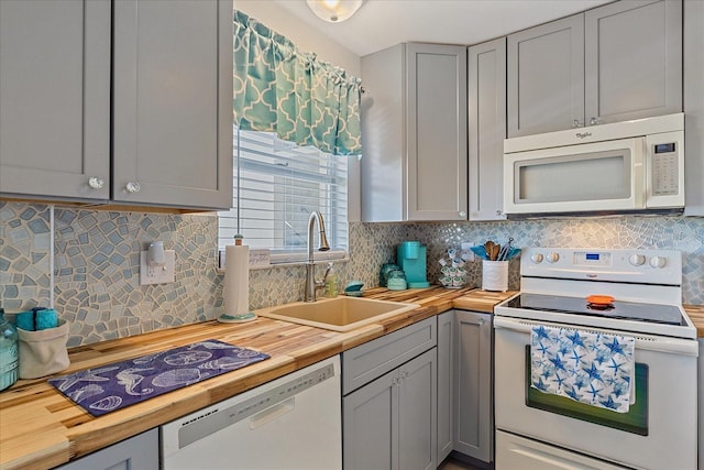 kitchen featuring decorative backsplash, white appliances, sink, gray cabinets, and butcher block countertops