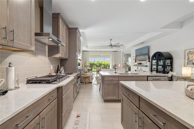 kitchen featuring appliances with stainless steel finishes, light stone counters, wall chimney exhaust hood, and sink