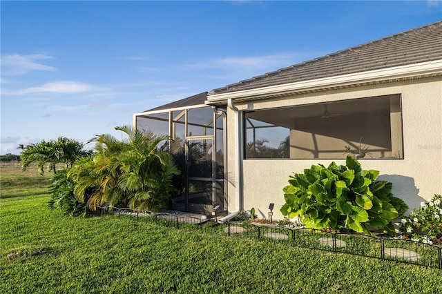 view of side of property featuring glass enclosure and a lawn