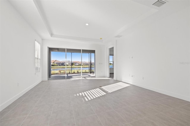 spare room featuring light tile patterned floors and a raised ceiling