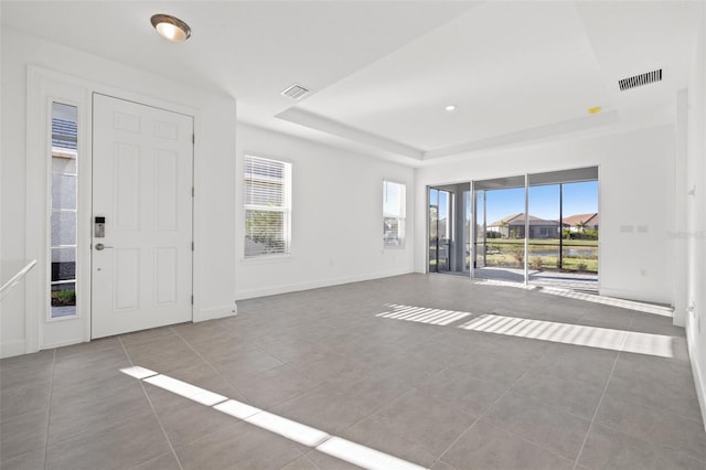 tiled entrance foyer with a raised ceiling and a healthy amount of sunlight