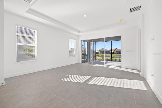 spare room featuring a raised ceiling and light tile patterned floors