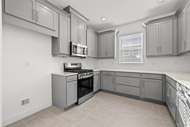 kitchen featuring gray cabinetry, stainless steel appliances, and light tile patterned flooring