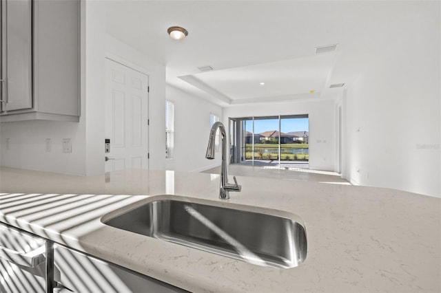 kitchen featuring gray cabinetry, sink, and a raised ceiling