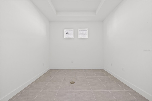 empty room with a raised ceiling and light tile patterned flooring