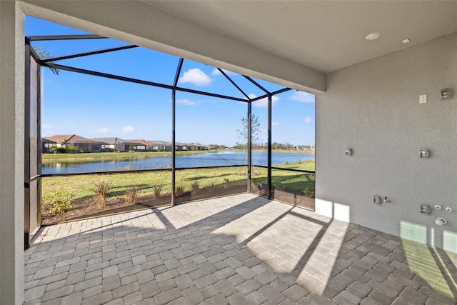 view of patio with a water view and glass enclosure