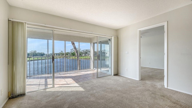 carpeted spare room featuring a textured ceiling and a water view