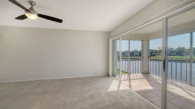 carpeted spare room with a textured ceiling, a water view, and ceiling fan