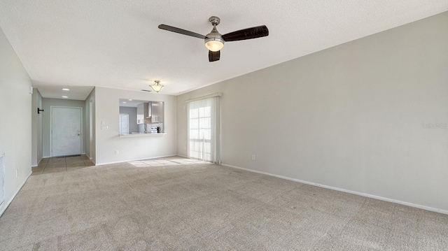 empty room featuring ceiling fan, light colored carpet, and a textured ceiling